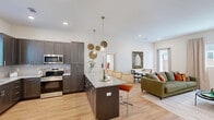 Located at 411 SW Stone Blvd in Bentonville, Arkansas, this single-story home offers a thoughtfully designed open-concept floor plan that maximizes every square foot. Light hardwood flooring flows throughout, tying the spaces together with a clean, contemporary aesthetic.

The kitchen is a standout feature, showcasing dark wood cabinetry, granite countertops, stainless steel appliances, and a central island with pendant lighting—ideal for both meal preparation and casual dining. The kitchen opens seamlessly into the living room, which is bright and welcoming thanks to multiple windows and a glass door that brings in natural light and outdoor views.

The primary bedroom is a comfortable retreat with ample natural light, a ceiling fan, and a well-organized walk-in closet with built-in shelving and hanging rods. The second bedroom features hardwood floors, a large window, and a built-in closet. A dedicated office provides a quiet workspace, complete with a window dressed with natural bamboo shades.

Three full bathrooms serve the home, including one with a tub-shower combination and a window for natural ventilation. A hallway connects the private areas of the home efficiently. The overall design balances modern finishes with functional layouts, making this Bentonville home both practical and inviting.