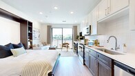 Located at 3606 Rainbow Blvd in Kansas City, KS, this thoughtfully designed studio maximizes every square foot through smart layout planning and modern finishes. Light hardwood flooring runs throughout the open-plan living area, creating a warm, cohesive feel. A large picture window and sliding balcony door flood the space with natural light while offering pleasant views of the surrounding greenery and cityscape.

The kitchen is well-appointed with two-tone cabinetry — white uppers paired with rich dark wood lowers — complemented by crisp white quartz countertops and a classic subway tile backsplash. Stainless steel appliances, including a range, over-the-range microwave, dishwasher, and refrigerator, provide full cooking functionality.

A built-in Murphy bed with integrated dark wood shelving serves as the centerpiece of the living area, cleverly combining sleeping and storage needs without sacrificing floor space. Recessed lighting throughout keeps the interiors bright and clean.

The bathroom features large-format marble-look tile flooring, a warm wood vanity with ample storage, a white quartz countertop, and a full bathtub. The entry hallway provides a natural transition between the bathroom, closet, and the main living area, enhancing the overall flow of the space.