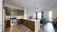 Located at 70 Music Square West in Nashville's iconic Music Row district, this 2-bedroom, 2-bathroom residence offers a well-designed single-level layout with contemporary finishes throughout. Wood-style flooring runs continuously across the living areas, tying the open-concept floor plan together seamlessly.

The kitchen is a standout feature, showcasing rich dark-wood cabinetry, a white quartz countertop, subway tile backsplash, and a full suite of stainless steel appliances. A large peninsula with seating for multiple bar stools doubles as a dining and prep space, while industrial-style pendant lights add a modern touch. The kitchen flows directly into the living room, which is bright and airy, featuring a ceiling fan and windows that invite natural light.

The primary bedroom is generously proportioned, offering ample space and a window with outdoor views. A dedicated closet provides wire-rack shelving and hanging storage for organization. Both bathrooms feature matching dark-wood vanities, dual sinks, white quartz countertops, and large framed mirrors, reflecting the cohesive design language found throughout the home.

Crisp white walls, recessed lighting, and clean architectural lines give the entire residence a polished, move-in-ready aesthetic in the heart of Nashville.