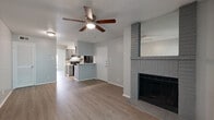 This thoughtfully designed 1-bedroom, 1-bathroom unit offers a functional and modern living environment spread across a single floor. The open-concept living area features light gray walls, updated luxury vinyl plank flooring throughout, and a textured ceiling. A standout architectural detail is the painted brick fireplace, which anchors the living room and adds character to the space. A sliding glass door leads to a private balcony, allowing natural light to fill the room and providing a pleasant outdoor connection. Ceiling fans are installed in both the living area and bedroom, enhancing comfort year-round. The galley-style kitchen is efficiently laid out with gray cabinetry, granite-look countertops, a stainless steel sink, mosaic tile backsplash, and black appliances including a refrigerator and electric range. The bedroom is a comfortable, well-proportioned space with a window offering natural light and a ceiling fan overhead. The bathroom is clean and functional, featuring gray cabinetry, granite-look countertops, an oversized mirror, and a tub-shower combination with white tile surround. Additional storage is provided by a louvered closet door visible in the living area. The unit presents a cohesive, neutral palette throughout, creating a bright and move-in ready atmosphere.