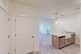 Located on Dellridge Place in Chattanooga, TN, this well-appointed 2-bedroom, 2-bathroom single-floor residence offers a clean, modern aesthetic throughout. The open-concept kitchen and living area serves as the heart of the home, featuring a large granite-topped island with an undermount sink, pendant lighting, white shaker-style upper cabinetry, warm-toned lower cabinets, and a full suite of stainless steel appliances including a refrigerator, range, and microwave. Light-toned luxury vinyl plank flooring runs throughout the main living areas, complementing the bright, neutral color palette. The living area is filled with natural light through large windows and a glass door that opens to an outdoor space. The spacious primary bedroom is carpeted for comfort and includes a ceiling fan, a dedicated en-suite bathroom with granite countertops, and a generous walk-in closet with wire shelving. The second bedroom is equally well-proportioned, also carpeted and featuring a ceiling fan. Additional highlights include a dedicated laundry room, a utility room, ample closet storage throughout, and a convenient hallway connecting all spaces. The overall layout is thoughtfully designed for both functionality and comfortable everyday living.