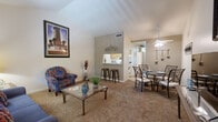 This single-floor residence offers a thoughtfully designed layout that balances comfort and functionality throughout. The open-concept living and dining area serves as the heart of the home, featuring vaulted ceilings that lend a sense of spaciousness and airiness. Soft carpeting runs throughout the main living spaces, adding warmth underfoot. A large window in the living room allows natural light to filter in, creating a bright and welcoming atmosphere.

The kitchen is configured as a galley-style space, lined on both sides with warm oak cabinetry and white laminate countertops, and is equipped with a range, refrigerator, and dishwasher. A pass-through bar with barstool seating connects the kitchen to the dining area, making it ideal for casual dining and entertaining. A ceiling fan with light fixture anchors the dining space overhead.

The residence includes two bedrooms, each featuring vaulted ceilings and plush carpeting. The primary bedroom benefits from natural light through vertical blinds and offers ample room for furnishings. The secondary bedroom is cozy and well-proportioned. The bathroom features warm oak cabinetry, a wide vanity with a large mirror, and hardwood-style flooring, providing a clean and functional space. Overall, the layout flows naturally from room to room, offering a practical and comfortable living environment.