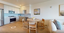 Unit 511 at The Minn, located in San Diego, CA, is a well-appointed 1-bedroom, 1-bathroom apartment spanning 640 square feet across a single floor. The open-concept kitchen and living area serves as the heart of the unit, featuring light wood-style flooring throughout. The kitchen is equipped with stainless steel appliances, including a French door refrigerator, gas range, built-in microwave, and dishwasher, complemented by two-tone cabinetry in white and taupe and a light blue subway tile backsplash. The living room offers generous natural light and direct access to a private balcony through a sliding glass door, providing elevated outdoor views of surrounding greenery. The 170-square-foot primary bedroom includes a window with balcony access, allowing additional natural light, and is complemented by a dedicated closet. The bathroom features a single-sink vanity with taupe cabinetry, white countertop, a large mirror with overhead lighting, and a shower with a curtain enclosure. Clean white walls, recessed and overhead lighting, and consistent flooring unify the space with a modern, minimalist aesthetic throughout.