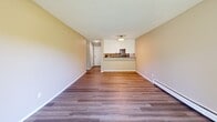 This single-floor, 1-bedroom, 1-bathroom residence in Sioux Falls, SD is thoughtfully laid out to maximize functionality and comfort. The open living area features durable wood-style flooring, a textured ceiling, and a sliding glass door that floods the space with natural light while providing direct access to an outdoor area with pleasant green views of surrounding trees and lawn. The kitchen is efficiently designed in a galley style, featuring white shaker cabinetry, dark granite-style countertops, a stainless steel refrigerator, and a double-basin sink — all complemented by wood-style plank flooring that ties the cooking and living spaces together. A peninsula counter connects the kitchen to the living area, enhancing the open feel. The bedroom is carpeted for warmth and comfort, equipped with a ceiling fan and a window that allows natural light and outdoor views. A dedicated closet provides convenient storage. A carpeted hallway connects the bedroom to the main living space. Baseboard heating is present throughout the unit, ensuring efficient climate control. The overall palette of warm neutral tones on the walls paired with clean white trim creates a cohesive and inviting atmosphere throughout the home.