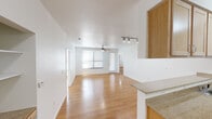 This single-story, one-bedroom, two-bathroom unit in Austin, TX offers a well-organized layout across a comfortable footprint. Warm hardwood-style flooring runs consistently throughout the space, lending a cohesive and clean aesthetic to every room.

The open-concept living, dining, and kitchen area forms the heart of the unit. The living room is generously sized, featuring a ceiling fan with light fixture, track lighting, and large windows fitted with horizontal blinds that allow ample natural light to fill the space. The kitchen is defined by a wraparound peninsula with granite-style countertops, light wood cabinetry, and stainless steel appliances including a refrigerator and electric range. A hallway connects the main living area to the private quarters.

The bedroom is a well-proportioned retreat with large windows, a ceiling fan, and access to a dedicated closet with built-in shelving and hanging rods. A second closet provides additional storage nearby. Both bathrooms are finished in a clean, neutral palette; one includes a tub/shower combination with white tile surround, light wood cabinetry, and grab bars. The overall ambiance of the unit is bright, functional, and move-in ready.