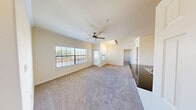 This 1-bedroom, 1-bathroom residence offers a thoughtfully designed single-floor layout that maximizes functionality and comfort. The open-concept kitchen serves as the heart of the home, featuring light wood cabinetry, dark granite countertops, a mosaic tile backsplash, and black appliances including a refrigerator, electric range, and microwave. A peninsula with a double stainless steel sink and additional counter space provides a natural transition into the living area. The living room is bright and welcoming, finished with plush carpet, a ceiling fan, and a large multi-pane window that invites natural light and outdoor views. Track lighting adds supplemental illumination near the kitchen transition. The bedroom is a comfortable, carpeted retreat with its own ceiling fan and window, offering a serene atmosphere. A dedicated walk-in closet adjacent to the bedroom provides ample wire-rack shelving and hanging space for organized storage. The bathroom is finished with wood-look flooring, a tiled soaking tub and shower combination, a granite-topped vanity, and clean white fixtures. A separate laundry room houses a full-sized washer and dryer along with a water heater, completing this efficient and well-equipped residence.