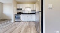 Located at 845 Trillium Park in Sarnia, Ontario, this well-appointed one-bedroom, one-bathroom unit offers a functional and modern living experience across a single floor. Light-toned hardwood flooring runs throughout the entire space, creating a cohesive and clean aesthetic.

The open-concept living and dining area is bright and airy, benefiting from large sliding glass doors that lead to a private balcony with views of surrounding trees. An additional window further enhances the natural light in this area. Baseboard heating is present throughout the unit.

The kitchen is efficiently designed and features crisp white shaker-style cabinetry, dark granite-look countertops, a subway tile backsplash, and a full suite of stainless steel appliances including a refrigerator, electric range with overhead exhaust fan, and a sink with modern fixtures.

The bedroom is a comfortable, well-proportioned space with its own window offering natural light and garden views, a built-in double closet for storage, and an additional walk-in closet area. Neutral beige walls throughout the unit provide a versatile backdrop.

The bathroom is finished with large-format beige tiles on both the floor and walls, and includes a full soaker tub and shower combination with chrome fixtures. The overall design of this unit is clean, modern, and move-in ready.