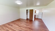 Located at 2201 Maple Valley Hwy in Renton, WA, this efficient single-floor unit offers a practical and well-organized layout comprising a living area and a kitchen. Throughout the space, warm-toned hardwood-style flooring lends a clean, cohesive look that ties the rooms together seamlessly.

The living area is bright and open, featuring crisp white walls, flush ceiling lighting, and a window that invites natural light into the room. A built-in closet with a sliding wood-panel door provides convenient storage directly within the living space, adding functionality without sacrificing floor area.

The kitchen is efficiently designed, offering warm wood cabinetry both above and below the counter, a single-basin sink, a light-toned laminate countertop, and a window above the sink that brings in additional natural light. White appliances — including a freestanding electric coil range and a full-size refrigerator — complete the kitchen's practical setup.

The overall ambiance of the unit is clean, neutral, and move-in ready, with a simple, functional aesthetic suited for those seeking a low-maintenance living space. Its location along Maple Valley Hwy provides convenient access to local amenities, transit routes, and the broader Renton community.
