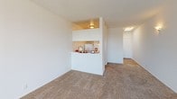 Located at 8503 Tobias Ave in the Panorama City neighborhood of Los Angeles, this single-floor unit offers a straightforward, functional layout designed to maximize open living space. The main living area is generously sized, finished with wall-to-wall carpeting that lends a warm, comfortable feel throughout. Large sliding glass doors fitted with vertical blinds open onto a private balcony, allowing abundant natural light to fill the space and providing pleasant outdoor views of the surrounding neighborhood. A wall-mounted air conditioning unit ensures year-round climate comfort.

The kitchen is positioned adjacent to the living area and features a pass-through counter that connects the two spaces, promoting an open and airy atmosphere. Light-toned cabinetry offers ample storage, and the kitchen is equipped with a sink and essential appliances. A skylight near the hallway further brightens the interior, drawing additional natural light into the unit.

The bathroom is well-appointed with a wide vanity featuring generous counter space, an extended mirror, and wood-look flooring that contrasts cleanly with the bright white walls. The overall design of the space is clean and neutral, with white walls and textured ceilings that provide a versatile backdrop ready for personalization. The single-level layout ensures easy accessibility throughout.