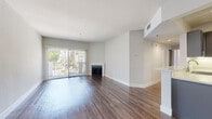 This well-appointed 2-bedroom, 2-bathroom residence in Los Angeles offers a thoughtfully designed single-floor layout with a clean, modern aesthetic throughout. Rich hardwood-style flooring flows seamlessly across the living spaces, complementing the neutral palette of soft gray and white walls.

The bright and open living room serves as the centerpiece of the home, anchored by a classic fireplace and floor-to-ceiling sliding glass doors that open to a private balcony, flooding the space with natural light and offering pleasant outdoor views of the surrounding greenery.

The kitchen is well-equipped with dark, contemporary cabinetry, light stone countertops, stainless steel appliances including a gas range, built-in microwave, and a double-basin sink — making it both functional and stylish.

The primary bedroom is generously sized, featuring a large mirrored sliding-door closet and ample natural light. The second bedroom benefits from a charming corner bay window arrangement that frames outdoor views and enhances the sense of space.

Both bathrooms are finished with dark vanity cabinetry, stone-style countertops, chrome fixtures, and full tub-shower combinations with wood-look flooring, maintaining a consistent modern design throughout the home.