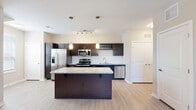 Located in Colorado Springs, CO, this single-floor residence offers a thoughtfully designed open-concept layout that blends modern style with everyday functionality. The kitchen serves as the centerpiece, showcasing rich dark cabinetry, granite countertops, a classic subway tile backsplash, and a full suite of stainless steel appliances including a refrigerator with ice maker, range, microwave, and dishwasher. A built-in wine rack adds a distinctive touch, while a spacious central island with a granite surface provides additional prep and seating space. Pendant lighting and a track light fixture illuminate the kitchen, complementing the light hardwood-style flooring that flows throughout the main living areas. The living room is bright and airy, featuring a ceiling fan, large windows with slatted blinds that invite natural light, and a neutral color palette that creates a calm, welcoming atmosphere. The bathroom is finished with a dark vanity, granite countertop, framed mirror, and modern light fixture, maintaining the cohesive design language of the home. A carpeted bedroom area with dual windows offers a quiet retreat. The overall ambiance is clean, contemporary, and move-in ready.