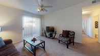 Located on N Fontana Ave in Tucson, Arizona, this single-story unit offers a well-organized layout designed for comfortable everyday living. The living room serves as the central gathering space, featuring vaulted ceilings, a ceiling fan with light fixture, and a large sliding glass door fitted with vertical blinds that allow abundant natural light to fill the room. Soft carpeting runs throughout the living areas and bedrooms, contributing to a warm, relaxed atmosphere.

The kitchen is designed in a classic galley configuration, with white cabinetry lining both sides, grey laminate countertops, and wood-look flooring. It includes a full suite of white appliances—refrigerator, dishwasher, and range—along with ample cabinet storage extending to the upper walls.

The unit includes two bedrooms, each carpeted and equipped with windows featuring vertical blinds. The primary bedroom connects directly to a private en-suite bathroom, which offers a wide vanity with generous under-sink cabinet storage, a large mirror with overhead lighting, and a separate water closet. A second full bathroom provides a single-sink vanity and a tub-shower combination with wood-look flooring. The thoughtful layout and neutral finishes throughout give the space a clean, move-in-ready appeal.