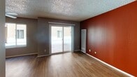 Located at 2461 Warring St, Apt 111 in Berkeley, California, this single-floor apartment offers a practical and well-appointed layout. Throughout the unit, warm hardwood-style flooring provides a cohesive and inviting foundation.

The living area is a standout space, featuring a bold terracotta accent wall that adds a vibrant pop of color against neutral gray tones. A sliding glass door opens to an outdoor patio, allowing natural light to fill the room and providing a seamless connection to the exterior.

The galley-style kitchen is efficiently designed, lined on both sides with rich dark wood cabinetry and stone-toned countertops offering ample storage and prep space. Stainless steel appliances, including a refrigerator and electric range, complete the kitchen's functional setup.

The bedroom is a quiet, well-lit room with a large window overlooking the exterior, neutral wall tones, and an open closet with a shelving rod. The terracotta accent wall carries through here as well, giving the space a consistent design identity.

The bathroom includes a tiled shower-tub combination, a vanity with countertop space, and brushed nickel fixtures and towel bars. A textured ceiling is present throughout the unit, adding a classic residential character to each room.