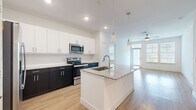 This thoughtfully designed 2-bedroom, 2-bathroom residence offers a comfortable and functional single-floor layout. The open-concept kitchen and living area serves as the heart of the home, featuring a large center island with granite countertops, an integrated sink, and pendant lighting overhead. The kitchen is equipped with stainless steel appliances, including a French door refrigerator, electric range, microwave, and dishwasher, complemented by a two-tone cabinet design of crisp white uppers and dark lower cabinets. Light wood-style flooring flows throughout the main living areas, enhancing the bright and airy atmosphere created by natural light from multiple windows. The living area includes a ceiling fan and direct access to an outdoor space. Both bedrooms are generously sized, with ceiling fans, natural light from large windows, and plush carpeting. The primary bedroom connects directly to a private en-suite bathroom featuring a granite vanity, walk-in shower with glass enclosure, and wood-look flooring, as well as access to a spacious walk-in closet with built-in shelving and hanging rods. The second bathroom mirrors the same clean, modern aesthetic with a granite vanity and a separate shower enclosure. Two dedicated closets throughout provide ample storage for everyday living.