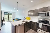 Located at 409 S 48th St in Lincoln, Nebraska, this well-designed one-bedroom, one-bathroom unit offers a thoughtfully arranged single-floor layout that makes excellent use of its compact footprint. Light-toned wood-style flooring flows throughout the main living areas, lending a clean, contemporary feel to the space.

The kitchen is a standout feature, equipped with stainless steel appliances — including a full-size refrigerator, electric range, and built-in microwave — dark espresso cabinetry, white quartz countertops, and a peninsula with bar seating, ideal for casual dining. Recessed lighting and a pendant fixture brighten the workspace efficiently.

The living room benefits from large floor-to-ceiling windows that invite abundant natural light and offer pleasant views of the surrounding tree canopy, creating a bright and airy atmosphere. The bedroom mirrors this quality, featuring its own oversized window with exterior views and plush carpeting for added comfort.

The bathroom is finished with wood-look tile flooring, dark cabinetry with a vanity, matte black hardware accents, and a walk-in shower. A dedicated in-unit laundry area houses a full-size side-by-side washer and dryer, adding everyday convenience. The overall design is modern, clean, and functionally efficient.