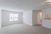 Located at 100 Bridgeport Cove Dr in Hampton, Virginia, this single-floor residence offers a clean, neutral aesthetic throughout. The open living area is generously proportioned, featuring soft wall-to-wall carpeting, a ceiling fan, and a large window that invites an abundance of natural light, creating a bright and airy atmosphere. A pass-through opening connects the living space to the kitchen, which is well-equipped with warm wood cabinetry, stone-toned countertops, a full-size refrigerator, and a range with a built-in overhead vent — all set atop durable hardwood-style flooring. The bedrooms are comfortably sized and carpeted, each featuring windows with blinds for natural light and privacy. At least one bedroom includes a built-in closet with a rod and shelf for organized storage. Two full bathrooms are present, each outfitted with a tub/shower combination and hardwood-style flooring, offering functional and practical design. Throughout the unit, crisp white walls and consistent neutral finishes create a cohesive, move-in-ready environment. The thoughtful layout provides clear separation between living, sleeping, and utility areas, making this a well-organized and practical living space.