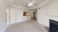 This single-floor, 3-bedroom, 2-bathroom residence offers a well-organized layout designed for comfortable everyday living. The open living room features a tray ceiling with a ceiling fan, neutral carpet, and sliding glass doors that lead to a balcony, filling the space with natural light. A pass-through window connects the living area to the kitchen, which is equipped with warm honey-toned wood cabinetry, a double sink, black appliances including a refrigerator and electric range, and durable wood-look flooring. The primary bedroom is generously sized, featuring plush carpet, a ceiling fan, a closet, and its own access to a hallway. Two additional bedrooms are carpeted, each with ceiling fans and windows that allow natural light. Both bathrooms are finished with wood-look flooring, warm wood vanity cabinetry, a tub-shower combination, and a wall mirror. The space also includes two closets with wire shelving for organized storage. Crisp white trim, neutral warm-toned walls, and consistent finishes throughout create a cohesive and clean aesthetic. Ceiling fans are present in multiple rooms, enhancing comfort. The layout flows naturally, making efficient use of the available space.