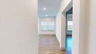 This thoughtfully designed 2-bedroom, 3-bathroom single-story residence offers a clean, modern aesthetic characterized by crisp white walls, light wood-style flooring, and an abundance of natural light streaming through multiple windows fitted with horizontal blinds. The open-concept living area seamlessly integrates the living room, dining room, and kitchen into one cohesive space, ideal for everyday living and entertaining. The kitchen is a standout feature, showcasing rich dark-stained cabinetry, granite countertops with distinctive speckled patterning, a large central island with a double stainless steel sink, pendant lighting, and a full suite of stainless steel appliances including a refrigerator, range, and over-the-range microwave. A dedicated pantry adds practical storage. The dining area benefits from multiple windows on two walls, filling the space with natural light. Both bedrooms are well-sized, with the primary bedroom offering comfortable proportions and natural light. The three bathrooms are finished consistently with dark wood vanities, granite countertops, and framed mirrors — one featuring a walk-in glass shower and another a tub/shower combination with white tile surround. Additional conveniences include four closets, in-unit laundry, and multiple hallways connecting the layout efficiently.
