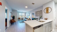 Located at 73 Brownstone Way in Englewood, NJ, this well-appointed single-floor residence offers a thoughtfully designed open-concept layout with modern finishes throughout. The kitchen serves as a central hub of the home, featuring a large quartz-topped island with bar seating, gray shaker-style cabinetry, a subway tile backsplash, stainless steel appliances including a gas range, microwave, and refrigerator, and light hardwood-style flooring. The kitchen flows seamlessly into the bright and airy living area, where large windows invite abundant natural light and views of the surrounding greenery. The living room is a welcoming space with soft, neutral tones and hardwood-style flooring. The bedrooms are carpeted for comfort, each offering natural light through well-sized windows, providing a calm and restful atmosphere. The bathrooms are finished with large-format tile flooring, white cabinetry, dark countertops, and modern vanity lighting, delivering a clean and contemporary aesthetic. An in-unit washer and dryer area adds convenience. Soft blue-gray walls carry throughout the home, creating a cohesive, tranquil ambiance that complements the modern design. This residence combines practical functionality with refined style in a desirable Englewood location.