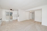 Located in the Rancho Peñasquitos neighborhood of San Diego, this 2-bedroom, 1-bathroom residence offers a comfortable and functional single-floor layout. The living room is bright and open, featuring plush carpeted flooring, a wall-mounted HVAC unit, and a large window that frames views of surrounding greenery, filling the space with natural light. The galley-style kitchen is clean and efficient, outfitted with white cabinetry, light stone countertops, a double-basin sink, and white appliances including a refrigerator and range, all complemented by warm wood-look flooring. Both bedrooms are carpeted and feature ceiling fans with light fixtures, mirrored sliding closet doors, and windows that bring in natural light. The primary bedroom offers a comfortable footprint with ample closet space. The shared bathroom is well-appointed with a vanity topped with marble-style countertops, white cabinetry, a tub-shower combination, and wood-look flooring, with a small window above the tub adding ventilation and light. A hallway connects the rooms, contributing to a cohesive and easy-to-navigate floor plan. The overall ambiance is clean, neutral, and move-in ready.