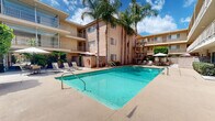 Regency Garden Apartments is a multi-story residential community located at 5151 Woodman Ave in the Sherman Oaks neighborhood of Los Angeles, California. The property is designed around a central courtyard that serves as the social and recreational heart of the complex.

The standout feature of the community is its generously sized outdoor swimming pool, framed by a spacious sun deck furnished with lounge chairs and shaded umbrella tables — ideal for relaxing in the Southern California sunshine. Tall, mature palm trees rise alongside the building, lending a classic Los Angeles aesthetic to the courtyard setting. Neatly trimmed hedges and lush greenery line the perimeter walkways, enhancing the garden-like atmosphere suggested by the community's name.

The multi-level building features private balconies on upper floors, offering residents elevated views of the courtyard and surrounding landscape. Ground-floor units benefit from direct access to the outdoor common areas, with well-maintained pathways connecting the various sections of the property. Stairwells provide access between floors and are integrated into the building's warm stucco exterior.

The overall ambiance of the property is that of a tranquil, resort-inspired retreat set within an accessible and established Los Angeles neighborhood, combining practical residential living with comfortable outdoor amenities.