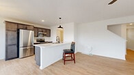 Located at 3355 Union St in North Chili, NY, this three-bedroom, three-bathroom home is thoughtfully laid out across three floors. The main level features an open-concept kitchen and living area with light hardwood-style flooring throughout. The kitchen is equipped with dark espresso cabinetry, stainless steel appliances including a refrigerator, range, microwave, and dishwasher, and a central island with a white countertop and pendant lighting — ideal for both cooking and casual dining. The living area is bright and airy, enhanced by a ceiling fan and a sliding glass door flanked by windows that invite natural light and provide outdoor views. A clean, modern front entry door with sidelights welcomes residents and guests. The upper floors host three carpeted bedrooms, including a generously sized primary bedroom, and well-appointed bathrooms with light, neutral finishes and black hardware accents. A dedicated laundry room includes a full-size washer and dryer. The unfinished basement offers utility space housing mechanical systems and presents opportunity for future use. Throughout, the home maintains a clean, contemporary aesthetic with neutral tones and light flooring, creating a cohesive and inviting atmosphere.