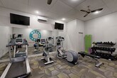 Located at Telephone Factory Lofts — a historic property established in 1938 — on Ralph McGill Boulevard in Atlanta, GA, this well-equipped fitness center offers residents a convenient and functional space to maintain an active lifestyle. The room is finished with a drop tile ceiling, recessed lighting, and ceiling fans that help maintain a comfortable environment during workouts. A wall-mounted split AC unit provides additional climate control.

The fitness center is outfitted with a variety of cardio equipment, including treadmills, an elliptical trainer, and a stationary bike, each positioned on protective floor mats atop the patterned, multi-tone carpet. A cable machine and weight bench round out the strength training options, while a tiered dumbbell rack and kettlebell set offer a full range of free weight choices. Stability balls and a yoga mat are also available for stretching and functional fitness work.

Full-length mirrors line one wall, amplifying the sense of space and allowing users to monitor their form during exercise. Multiple flat-screen TVs are mounted on the walls, providing entertainment options throughout any workout. A bold, circular rotary dial graphic — a nod to the building's telephone factory heritage — serves as a striking mural on the exposed painted brick accent wall, adding character and a sense of place to the space.