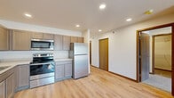 Located at 1330 Main Ave in Moorhead, MN, this single-floor residence offers three bedrooms, two bathrooms, and a thoughtfully organized layout across a comfortably sized footprint. Light wood-look flooring flows through the main living areas, lending a clean, cohesive aesthetic throughout.

The kitchen is a functional highlight, equipped with stainless steel appliances including a refrigerator, electric range, over-the-range microwave, and dishwasher. Warm-toned shaker-style cabinetry provides generous storage, while recessed lighting brightens the space efficiently. The kitchen opens toward the living area, supporting a connected, open feel.

The living room benefits from natural light and access to a balcony, adding a welcoming outdoor element to the space. Baseboard heating is present throughout, ensuring consistent warmth during Minnesota winters.

The bedrooms feature plush carpeting and are serviced by three closets, including a spacious walk-in closet with wire shelving for organized storage. The primary bedroom is generously sized with its own closet access. Both bathrooms are finished with light wood-tone vanities and durable luxury vinyl flooring.

A dedicated in-unit laundry area houses a full-size Whirlpool washer and dryer set with overhead wire shelving. The overall design is clean and neutral, offering a versatile canvas for any furnishing style.