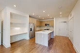 Located at 285 Mayson Ave NE in Atlanta's vibrant Inman Park neighborhood, this modern 2-bedroom, 2-bathroom residence offers a thoughtfully designed single-story layout with contemporary finishes throughout. The open-concept living, dining, and kitchen area serves as the heart of the home, featuring warm wood-tone flooring that flows seamlessly across the entire space. The kitchen is a standout, outfitted with flat-front light wood cabinetry, a stone tile backsplash, stainless steel appliances including a French door refrigerator and range, and a central island with a white quartz countertop and undermount sink — ideal for both cooking and casual dining. Built-in open shelving adds a functional architectural detail to the living area. The bedrooms are bright and well-proportioned, with the primary bedroom offering access to an outdoor space. Each bedroom is served by its own bathroom; the bathrooms feature large-format marble-style tile flooring, glass-enclosed walk-in showers, floating wood vanities with white countertops, and modern fixtures. Additional highlights include four closets, an in-unit laundry area, recessed lighting throughout, and ceiling fans in the bedrooms. The clean, neutral palette and modern design create a fresh and cohesive living environment.
