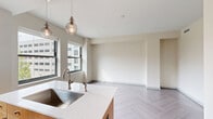 Located at 2701 Park Ave in Detroit's Midtown neighborhood, this one-bedroom, one-bathroom residence offers a thoughtfully designed single-floor layout. The open living area is anchored by striking herringbone-patterned flooring that flows throughout the unit, lending a refined, contemporary character to the space.

The kitchen is a standout feature, equipped with stainless steel appliances including a refrigerator, range, and microwave. Warm wood cabinetry on the island contrasts beautifully with sleek dark upper cabinets and a classic white subway tile backsplash. Pendant lighting over the kitchen island adds an inviting, modern touch.

The bedroom is a well-proportioned retreat featuring large windows that frame views of the surrounding Detroit cityscape, filling the room with natural light. Panel-style doors in a soft gray finish lead to a closet and connect to the hallway, adding a clean architectural detail.

The bathroom is finished with crisp white subway tile and features a glass-enclosed walk-in shower with hexagonal mosaic floor tile, a built-in shelf, and matte black accents that provide a stylish contrast to the bright, clean surroundings.

Throughout the unit, neutral warm-white walls, consistent flooring, and modern finishes create a cohesive, move-in-ready aesthetic suited to urban living in Detroit.