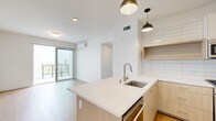 Located in the vibrant Park Boulevard corridor of San Diego's North Park neighborhood, this 2-bedroom, 1-bathroom residence offers a clean, modern aesthetic throughout. Light-toned hardwood flooring runs continuously across the open-concept living and kitchen area, creating a warm and cohesive feel. The kitchen is a standout feature, equipped with stainless steel appliances including a gas range, microwave, and refrigerator, complemented by light wood cabinetry, white subway tile backsplash, and a quartz-topped island with an undermount sink and pendant lighting. The living area flows naturally toward a sliding glass door that opens onto a private balcony with outdoor views. Both bedrooms are bright and airy, featuring light wood floors, sliding glass doors or tall windows that bring in abundant natural light, and wall-mounted mini-split HVAC units for individual climate control. The primary bedroom includes a built-in closet with shelving and hanging rods. The bathroom is finished with vertical white tile in a glass-enclosed walk-in shower, classic hexagonal mosaic floor tile, and open shelving. A hallway connects all rooms efficiently, maximizing the well-utilized floor plan of this thoughtfully designed San Diego residence.