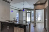Located at 31 Perimeter Center E in Dunwoody, Georgia, this single-floor residence offers a thoughtfully designed layout with a blend of modern finishes and functional living spaces. The open-concept kitchen is a standout feature, showcasing dark espresso cabinetry, dark granite countertops, a tile backsplash, stainless steel appliances, and a peninsula with a double sink — all illuminated by stylish pendant lighting and a track lighting system overhead. Crown molding adds a refined touch throughout the space.

The living area transitions seamlessly from the kitchen, featuring warm hardwood flooring and a tray ceiling with elegant crown molding detailing. Large windows along the exterior wall invite an abundance of natural light and provide views of the surrounding greenery. The entry foyer features tile flooring, providing a clean and practical transition into the home.

The bedroom is bright and airy, with hardwood flooring, a ceiling fan, and a large window fitted with blinds. The bathroom is well-appointed with a granite vanity, dark cabinetry, a large mirror, tile flooring, and a tiled bathtub and shower combination. A dedicated laundry area with in-unit washer and dryer hookups adds everyday convenience. Overall, the space offers a modern, comfortable, and functional living environment.