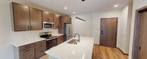This contemporary 620 square foot apartment in Madison, Wisconsin, offers a thoughtfully designed living space. The open floor plan maximizes efficiency, seamlessly blending the living area with the kitchen. The kitchen is a standout feature, boasting modern wooden cabinetry, stainless steel appliances, and a spacious island with a sink, perfect for both meal preparation and casual dining.

The bedroom, measuring 130 square feet, is generously sized for a one-bedroom unit. It features a large window that floods the space with natural light and provides views of the surrounding area. The apartment's hardwood flooring runs throughout, adding warmth and continuity to the space.

The bathroom is well-appointed with modern fixtures, including a bathtub-shower combination and ample storage space. The apartment also includes a closet for additional storage.

Recessed lighting throughout the apartment contributes to the modern aesthetic while providing ample illumination. The unit's design emphasizes clean lines and a neutral color palette, creating a versatile canvas for personal decor styles.

Located in a prime area of Madison, this apartment offers a blend of style, functionality, and urban convenience, making it an ideal residence for singles or couples seeking a contemporary living space.
