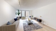 Located at 233 E Wacker Drive in Chicago's Streeterville neighborhood, this one-bedroom, one-bathroom residence offers a well-organized layout with light wood flooring throughout and a bright, neutral color palette. The spacious living room is a standout feature, anchored by expansive floor-to-ceiling windows that flood the space with natural light and frame views of the surrounding Chicago skyline. Track lighting overhead and clean white walls contribute to an open, airy ambiance. The kitchen is outfitted with white shaker-style cabinetry, stainless steel appliances including a refrigerator, range, and dishwasher, and light countertops — delivering a clean, functional design. A hallway connects the main living areas to the private bedroom, which features its own large window with city views, light wood flooring, and ample room for furnishings. Three closets provide generous storage throughout the residence. The bathroom includes a full tub-shower combination with white tile surround and classic chrome fixtures. The overall design of this residence is modern and understated, with consistent finishes that create a cohesive and comfortable living environment in one of Chicago's most sought-after urban locations.