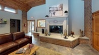 Parkridge is a thoughtfully designed single-floor community space that blends rustic charm with modern functionality. The main lounge area is an immediate showstopper, anchored by a grand brick fireplace with a white mantel surround and a wall-mounted television, creating a warm and inviting focal point. Soaring vaulted ceilings clad in warm natural wood paneling add a sense of openness and character, while slate tile flooring runs throughout, tying the spaces together cohesively. Clerestory windows positioned high along the walls allow natural light to filter in, enhancing the bright and airy atmosphere.

The fully equipped kitchen features rich honey-toned wood cabinetry, dark granite countertops, stainless steel appliances including a range and over-the-range microwave, and a deep basin sink — providing everything needed for convenient meal preparation and entertaining.

Adjacent to the lounge, a dedicated fitness area offers cardio equipment including a treadmill and elliptical machine, alongside comfortable leather seating and a wall-mounted television. Large floor-to-ceiling windows and glass doors in the fitness space provide direct sightlines to the lush outdoor surroundings, creating an energizing environment. Exposed brick accents throughout lend a timeless, welcoming quality to the entire space.