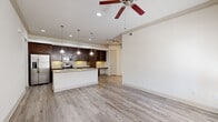This thoughtfully designed single-story home offers a comfortable and functional layout across its one floor. The open-concept kitchen and living area serves as the heart of the home, featuring rich dark-stained cabinetry, granite countertops, a central island with an undermount sink, and stainless steel appliances. Pendant lighting illuminates the island, while a built-in desk area with open shelving provides a practical workspace. Light-toned hardwood-style flooring flows throughout the main living areas, complemented by crown molding and a ceiling fan that enhance the space's refined character. The bedroom is generously sized, finished with plush carpet, a ceiling fan, and natural light from dual windows. A walk-in closet with wrap-around shelving and hanging rods offers substantial storage. The full bathroom impresses with a dual-sink vanity topped with granite, dark cabinetry, tile flooring, and an arched soaking tub alcove. Hallways connect the spaces efficiently, and an attached single-car garage with an automatic opener provides secure, convenient parking. Neutral tones and consistent finishes throughout create a cohesive, move-in-ready ambiance.