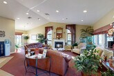Located at 26 Sea Breeze Dr in South Dartmouth, MA, this generously sized single-floor community clubhouse offers a comprehensive range of amenities across a well-organized layout. The inviting main lounge features vaulted ceilings with recessed lighting, a classic wood-trimmed fireplace, large windows dressed with decorative curtains, and plush leather seating arranged around a glass-topped coffee table — all complemented by lush indoor plants that add warmth and life to the space. Adjacent to the lounge, the hallway connects seamlessly to the office area, which features bold accent walls, built-in workstations, and tile flooring, providing a professional and functional environment. The game room offers light hardwood-style flooring, a full-size pool table, and open space ideal for recreational activities. The fitness center is well-equipped with treadmills, stationary bikes, and additional exercise equipment, all bathed in natural light from a bank of large windows overlooking the surrounding grounds. The laundry facility is spacious and efficiently arranged with rows of commercial washers and dryers, light wood-style flooring, and ample folding space. Additional spaces include a library, a dedicated office, and practical support areas, making this a fully functional and community-focused facility.