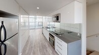 Located at 2015 Hancock in San Diego, Unit #120 at the Allure community is a thoughtfully designed two-floor residence that blends contemporary style with functional living. The open-concept kitchen is a standout feature, showcasing high-gloss white cabinetry, gray quartz countertops, a glass tile backsplash, and a full suite of stainless steel appliances including a built-in oven, cooktop, and microwave. Floor-to-ceiling windows along the kitchen and living areas flood the space with natural light and frame views of the surrounding exterior. Light wood-look flooring runs throughout the main living areas, lending a clean and modern aesthetic. The bedrooms are carpeted for comfort, with one featuring a ceiling fan, window blinds, and access to natural light, while another opens directly to the outdoors through a sliding glass door. Mirrored sliding closet doors add depth and brightness to the bedroom spaces. The bathrooms are distinctly styled — one features vibrant green mosaic tile on the accent wall, marble-look tile flooring, a wall-mounted sink, and recessed lighting, while the second is finished in a crisp, minimalist white. The two-floor layout provides a versatile and well-organized living environment suited for a variety of lifestyles.