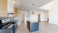 This modern single-story residence in Fayetteville, Arkansas offers a thoughtfully designed layout with two bedrooms, two bathrooms, and in-unit laundry. The open-concept living and kitchen area serves as the heart of the home, where dramatically tall ceilings and clerestory windows flood the space with natural light. The kitchen is outfitted with stainless steel appliances, including a side-by-side refrigerator, range, and dishwasher, complemented by light wood cabinetry, open shelving, and a substantial dark-toned island with pendant lighting overhead.

The living area extends the clean, airy aesthetic with large windows providing outdoor views and ample daylight. The primary bedroom features soaring ceilings, a ceiling fan, generous closet storage, and large windows. The second bedroom is equally bright and well-proportioned. Each bathroom reflects a modern, minimalist style—one featuring a sleek glass-enclosed walk-in shower with white tile surround, the other a full tub-shower combo with dark vanity cabinetry. The dedicated laundry room includes a stacked washer and dryer alongside built-in shelving for added storage convenience throughout.