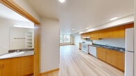 Located at 1801 E Yesler Way in Seattle's vibrant Capitol Hill neighborhood, this two-bedroom, one-bathroom unit offers a well-designed, efficiently utilized floor plan. Light hardwood flooring runs throughout, creating a warm and cohesive aesthetic across every room.

The kitchen is a standout feature, outfitted with warm honey-toned wood cabinetry extending to the ceiling for ample storage, dark countertops, and a full suite of white appliances including a range, dishwasher, and refrigerator. Recessed lighting keeps the space bright and functional. The kitchen flows naturally into the open living area, which benefits from a large window that brings in natural light and outdoor views.

The primary bedroom features large windows overlooking the surrounding neighborhood, filling the room with natural light. The second bedroom also includes a window with outdoor views and offers a built-in closet with sliding wood doors, providing practical storage. Both rooms continue the light hardwood flooring seen throughout the unit.

The bathroom is clean and well-appointed, featuring warm wood cabinetry, a dark stone-style countertop, a large mirror, and accessible grab bars. Light flooring ties the space together seamlessly. This unit offers a functional and comfortable layout ideal for urban Seattle living.