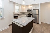 Located at 1000 Infinity Dr in Maryville, Tennessee, this two-story residence offers a well-designed layout with thoughtful finishes throughout. The main level is anchored by a striking open-concept kitchen and living area, highlighted by dramatic vaulted ceilings that lend an airy, expansive feel to the space. The kitchen is equipped with stainless steel appliances, white shaker-style cabinetry, a granite-topped island with pendant lighting above, and light hardwood flooring that extends throughout the main living areas. Natural light filters in through multiple windows dressed with classic white blinds.

A staircase with carpet treads and clean white walls connects the two floors, leading to the upper level. The upper floor features bedrooms with soft wall-to-wall carpeting, ceiling fans, and windows that bring in natural light. One bedroom is distinguished by a vaulted roofline, adding architectural character to the room.

The bathrooms are finished with granite-topped vanities, white cabinetry, and hardwood flooring. A full bathroom includes a soaking tub and shower combination, while the primary bath provides direct access to a walk-in closet outfitted with wire shelving and hanging racks. The overall aesthetic is clean, neutral, and move-in ready, reflecting a modern yet comfortable design sensibility.
