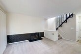 Located at 1997 Villa Rd in Birmingham, Michigan, this two-bedroom, one-bathroom multi-level home spans three floors, offering a well-organized layout with dedicated spaces for living, storage, and utility. The main living area is anchored by a striking wide brick fireplace with a black finish, complemented by plush carpeting and a sleek open staircase with black metal balusters that draws the eye upward. Large sliding glass doors and expansive windows flood the space with natural light, creating a bright and airy atmosphere throughout. The combined kitchen and dining area features crisp white cabinetry with black hardware, light wood-look flooring, a stainless steel sink, and a full range — with a glass door providing direct access to the outdoors. Both bedrooms are carpeted and well-proportioned, each with vertical blinds and ample natural light; the primary bedroom includes a mirrored closet. The full bathroom is finished with clean white subway tile, wood-look tile flooring, a wide vanity with marble-style countertop, and a soaking tub. The unfinished basement offers generous utility and storage potential, complete with a utility sink and open ceiling for easy access to mechanical systems. Multiple closets throughout the home add further convenience.