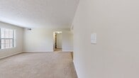 This single-story residence at 6648 Maple Glen Dr, Indianapolis, offers 830 square feet of living space. The layout includes two bedrooms, a living room, kitchen, and hallway. The primary bedroom is notably spacious at 190 square feet, providing ample room for comfortable living.

The interior features a neutral color palette with beige walls and carpeting in most rooms, creating a cohesive and calming atmosphere. Large windows with horizontal blinds allow for natural light and privacy control. The living area showcases a combination of carpeted and hardwood flooring, adding visual interest and defining separate spaces within the open plan.

A striking feature is the white railing leading to what appears to be a lower level, suggesting additional space not included in the main floor square footage. The kitchen, while compact, includes wooden cabinetry and white countertops, with a separate area for laundry facilities.

Sliding closet doors in the bedrooms maximize space efficiency. The overall design emphasizes functionality and simplicity, ideal for those seeking a low-maintenance living environment. The neutral decor provides a blank canvas for personalization, allowing future occupants to easily adapt the space to their style preferences.