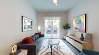 This well-designed one-bedroom, one-bathroom residence offers a thoughtfully organized single-story layout that maximizes functionality and style. The open-concept living area features dark hardwood-style flooring, a ceiling fan, and a sliding glass door that floods the space with natural light while providing direct access to a private balcony with outdoor seating. The living room comfortably accommodates a full seating arrangement and flows seamlessly into the kitchen and dining areas.

The kitchen is a standout feature, equipped with white shaker-style cabinetry extending to the ceiling, a subway tile backsplash, stainless steel appliances including a gas range, microwave, and French door refrigerator, and a quartz-topped island with undermount sink and bar seating. Pendant lighting adds a modern touch overhead.

The bedroom is carpeted and bright, benefiting from a large window with outdoor views. The full bathroom is finished in neutral tones with a white tile tub-shower surround, quartz countertop vanity, and light wood-look tile flooring. Throughout the unit, a neutral color palette and clean lines create a cohesive, contemporary ambiance.