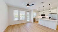 Located at 1601 Maguire Rd in Ocoee, FL, this well-appointed 2-bedroom, 2-bathroom residence offers a thoughtfully designed single-floor layout with a clean, contemporary aesthetic throughout. Light wood-tone flooring runs continuously across the living areas and bedrooms, lending warmth and visual cohesion to the space.

The open-concept kitchen and living area serves as the heart of the home, featuring white shaker cabinetry extending to the ceiling, a white quartz island with pendant lighting overhead, stainless steel appliances including a French door refrigerator and range, and a subway tile backsplash. Recessed and chandelier lighting complete the bright, inviting atmosphere.

Both bedrooms are generously proportioned, filled with natural light from large windows, and equipped with ceiling fans. The primary bedroom includes a double-door closet for ample storage. The two bathrooms are finished with beige tile flooring and dark oil-rubbed bronze fixtures; one features a glass-enclosed walk-in shower with white tile surround, while the other offers a soaking tub with shower combination.

A dedicated laundry room with overhead wire shelving provides practical convenience. The private balcony, framed by a black metal railing, overlooks a tranquil pond surrounded by lush greenery — a standout feature offering peaceful outdoor living.