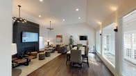Located at 31 Putnam Green in Greenwich, Connecticut, this thoughtfully designed clubhouse serves as a premier community gathering space. The single-floor layout is anchored by a dramatic great room featuring soaring vaulted ceilings that lend an open, airy feel throughout the space. Rich dark hardwood flooring flows seamlessly across the interior, providing a warm contrast to the crisp white walls and trim.

The lounge area is a standout centerpiece, showcasing a bold dark shiplap accent wall that frames both a wall-mounted flat-screen television and a sleek gas fireplace below. Comfortable sectional seating, a rustic wood coffee table, and vibrant patterned ottomans create an inviting setting for relaxation or socializing. A contemporary multi-arm chandelier adds a modern finishing touch overhead.

Adjacent to the lounge, a dedicated dining area offers a long communal table with patterned upholstered chairs, surrounded by large plantation-shuttered windows that fill the space with natural light and views of the surrounding landscape. An entry foyer with dark cabinetry, a white quartz countertop, and decorative accents provides a refined welcome upon arrival. Throughout the clubhouse, carefully curated artwork and lush potted greenery contribute to a polished, cohesive aesthetic.