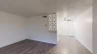 Located at 10517 Ashwood Dr in El Paso, TX, this two-story, 2-bedroom, 3-bathroom home offers a well-organized layout with equal living space distributed across both floors. The main level opens into a bright living and dining area distinguished by a striking decorative lattice partition — a retro-inspired design element that adds visual interest while maintaining an open feel. Painted white brick accent walls add texture throughout, complemented by durable hardwood-style flooring and a textured ceiling. A ceiling fan with integrated lighting keeps the space comfortable. The kitchen features white cabinetry, a subway tile backsplash, stainless steel appliances including a dishwasher and range, and light wood-tone flooring, creating a clean and functional workspace. A staircase connects to the upper floor, where both bedrooms are located. Each bedroom includes plush carpeting, ceiling fans, painted brick accent walls, and windows with blinds that allow natural light. Three closets provide ample storage across the home. The bathrooms are finished with white vanities topped with speckled countertops and full tub-shower combinations with white tile surrounds. Three hallways and a well-connected floor plan enhance the overall flow of this efficiently designed two-story home.