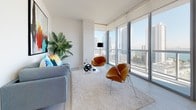 Suite 1606 is a thoughtfully designed high-rise residence that combines contemporary aesthetics with functional living. The open layout flows seamlessly across a single level, with clean white walls and light-toned tile and carpet flooring establishing a bright, cohesive atmosphere throughout.

The kitchen is a standout feature, equipped with stainless steel appliances including a French door refrigerator, electric range, built-in microwave, and dishwasher. Warm wood-grain cabinetry contrasted against white upper cabinets and light countertops lends a modern yet inviting character. A floor-to-ceiling window at the end of the kitchen frames expansive city and water views, flooding the space with natural light.

The living area continues this visual connection to the outdoors through large floor-to-ceiling windows offering panoramic skyline and bay views, creating an airy, elevated ambiance ideal for both relaxing and entertaining.

The bedrooms are carpeted and generously proportioned, with the primary bedroom benefiting from oversized windows that capture sweeping urban vistas. Both bathrooms feature wood-finish floating vanities, white countertops, large-format tile flooring, and tub-shower combinations with clean, minimalist detailing.