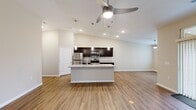 This thoughtfully designed single-floor residence offers 2 bedrooms and 2 bathrooms within a comfortable and functional layout. A welcoming entryway with hardwood-style flooring leads into the open-concept living, dining, and kitchen area, where vaulted ceilings and a ceiling fan create an airy, spacious atmosphere. Large windows allow natural light to flow throughout the main living area.

The kitchen is a standout feature, equipped with dark espresso cabinetry, granite countertops, stainless steel appliances including a refrigerator, range, and microwave, and a center island with a sink and pendant lighting above. The kitchen flows seamlessly into the dining and living areas, making it ideal for entertaining.

Both bedrooms are generously sized and feature plush carpeting, ceiling fans, and windows that bring in natural light. The primary bedroom is notably spacious, with ample room for furnishings. The two bathrooms are finished with dark cabinetry, granite-topped vanities, and hardwood-style tile flooring, with one bathroom featuring a full tub-shower combination.

Additional highlights include a dedicated laundry room with cabinetry, a closet for storage, and consistent neutral-toned walls throughout that complement the warm flooring, creating a clean, modern aesthetic across the entire residence.