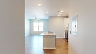 Located at Jefferson Ridge Drive in Jeffersonville, Indiana, this well-appointed one-bedroom, one-bathroom residence offers a thoughtfully designed layout with modern finishes throughout. The open-concept main living area seamlessly connects the kitchen, dining, and living spaces, all finished with durable wood-look flooring and recessed lighting. The kitchen is a standout feature, showcasing white shaker-style cabinetry, granite countertops, a central island with a built-in sink, and a full suite of stainless steel appliances including a refrigerator, range, and microwave. A ceiling fan overhead adds comfort to the bright living area, which receives natural light through a large window. The spacious primary bedroom is carpeted and features a generous window with outdoor views of the surrounding natural landscape. A versatile den offers additional flexible living space, also finished with wood-look flooring and natural light. The full bathroom includes a granite-topped vanity with white cabinetry, a tub-shower combination, and wood-look flooring. A dedicated laundry area houses the washer and dryer alongside the water heater and HVAC equipment. Three closets provide ample storage throughout the residence.